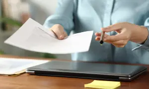 Ręce podają dokumenty, gotowe do podpisania. To ważny moment w karierze, test przedsiębiorcy.