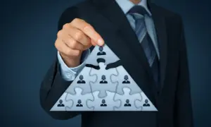 Biznesmen układa piramidę z puzzli, symbolizującą strukturę firmy i jej beneficjenta rzeczywistego.