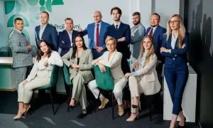 Zespół prawników w garniturach, pozujący do zdjęcia w nowoczesnym biurze.