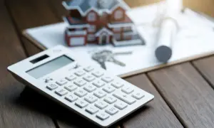 Kalkulator, klucze i makieta domu na dokumentach. Zastanawiasz się, hipoteka co to? To finansowanie zakupu nieruchomości.