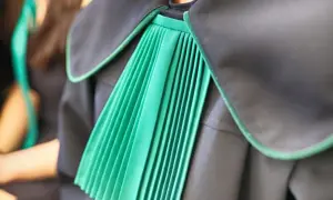 Zbliżenie na zieloną plisowaną szatę prawniczą z czarnym kołnierzem.