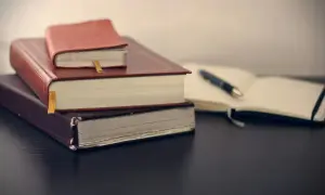 Stos książek i otwarty notatnik z długopisem. Czas na ugoda i zapisanie ważnych myśli.