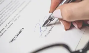 Podpisanie rachunku do umowy zlecenia. Dłoń z piórem podpisuje dokument.