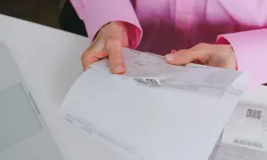 Dłonie trzymają dokumenty, na jednym z nich widnieje kwota 150,00 zł. To może być faktura uproszczona.