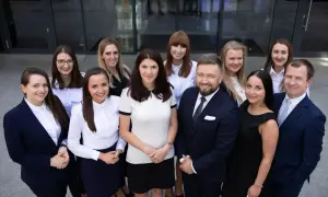 Grupa prawników w garniturach i strojach biznesowych przed budynkiem.