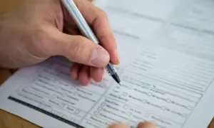 Dłoń z długopisem wypełnia formularz. Warto wiedzieć, jak sprawdzić swój NIP, by poprawnie wypełnić dokumenty.