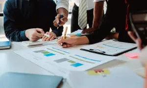 Zespół analizuje wykresy i dokumenty finansowe przy biurku.