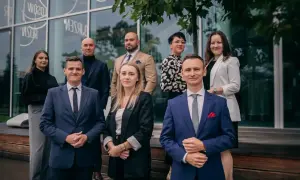 Grupa prawników w eleganckich strojach pozuje przed nowoczesnym budynkiem.