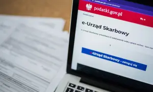 Laptop z otwartą stroną e-Urzędu Skarbowego. Obok leżą dokumenty, co sugeruje identyfikację zobowiązania podatkowego.