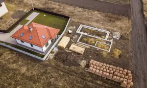 Budowa domu w zabudowie zagrodowej: fundamenty, drewno i cegły czekają na użycie.