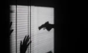 Cień dłoni z pistoletem grozi dwóm dłoniom, które próbują się zasłonić. To scena jak z filmu o świadku koronnym.