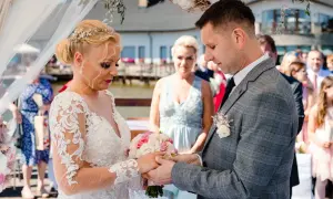 Para młoda podczas ceremonii ślubnej. Panna młoda w koronkowej sukni, pan młody w garniturze. Pytanie o to, odpis aktu małżeństwa ile ważny, nie ma związku z tą sceną.