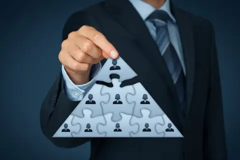 Biznesmen układa piramidę z puzzli, symbolizującą strukturę firmy i jej beneficjenta rzeczywistego.