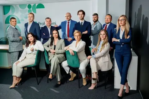 Zespół prawników w garniturach, pozujący do zdjęcia w nowoczesnym biurze.