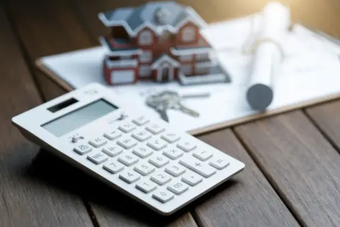 Kalkulator, klucze i makieta domu na dokumentach. Zastanawiasz się, hipoteka co to? To finansowanie zakupu nieruchomości.