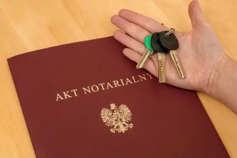 Akt notarialny i klucze w dłoni. Komparycja dokumentów i symbolu własności.