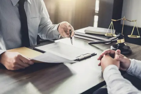 Prawnik wskazuje na aneks do umowy najmu okazjonalnego. Na stole młotek sędziowski i waga sprawiedliwości.