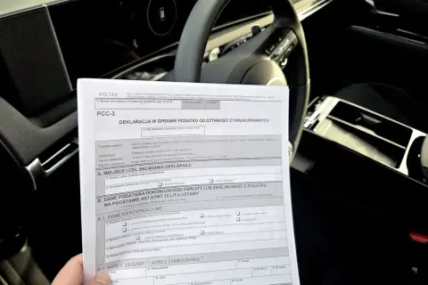 Formularz PCC-3, deklaracja podatku od czynności cywilnoprawnych, leży na kierownicy samochodu.