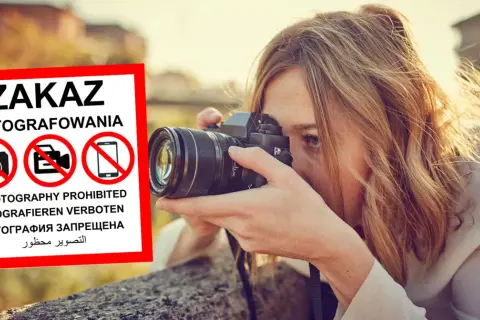 Kobieta z aparatem ignoruje znak zakaz fotografowania.
