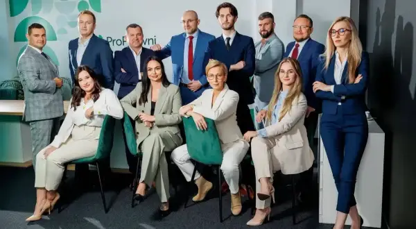 Zespół prawników w garniturach, pozujący do zdjęcia w nowoczesnym biurze.