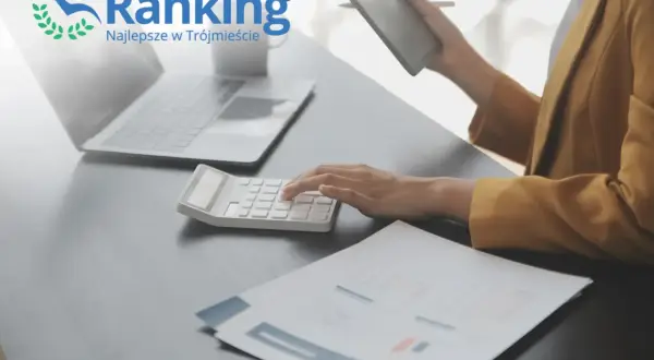 Ręce na kalkulatorze, laptop i tablet na biurku, logo "Ranking Najlepsze w Trójmieście".