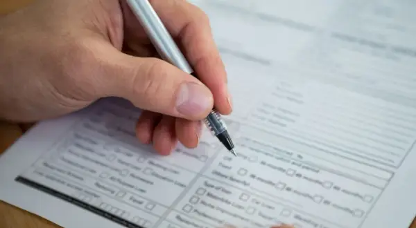 Dłoń z długopisem wypełnia formularz. Warto wiedzieć, jak sprawdzić swój NIP, by poprawnie wypełnić dokumenty.