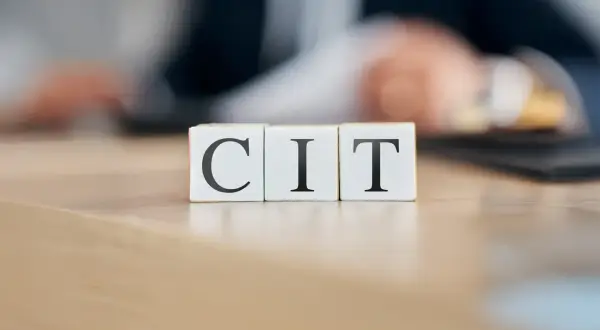 Trzy kostki z literami C, I, T. Symbolizują podatek CIT, który jest ważnym elementem finansów firm.