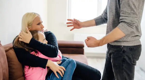 Matka tuli córkę, gdy mężczyzna groźnie gestykuluje. Sytuacja wygląda na napiętą, być może to 190 kk.