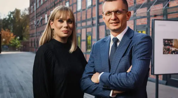Dwoje prawników w garniturach przed ceglanym budynkiem.