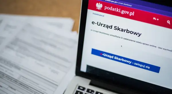 Laptop z otwartą stroną e-Urzędu Skarbowego. Obok leżą dokumenty, co sugeruje identyfikację zobowiązania podatkowego.