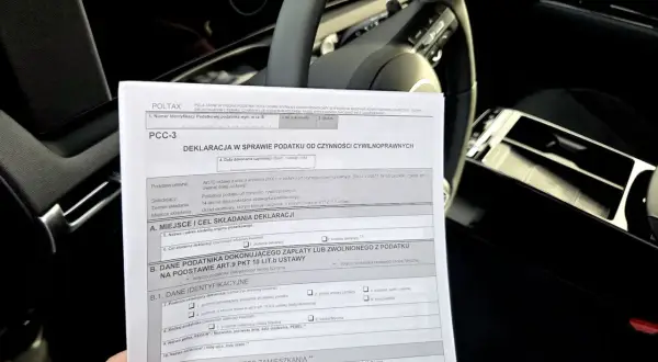 Formularz PCC-3, deklaracja podatku od czynności cywilnoprawnych, leży na kierownicy samochodu.