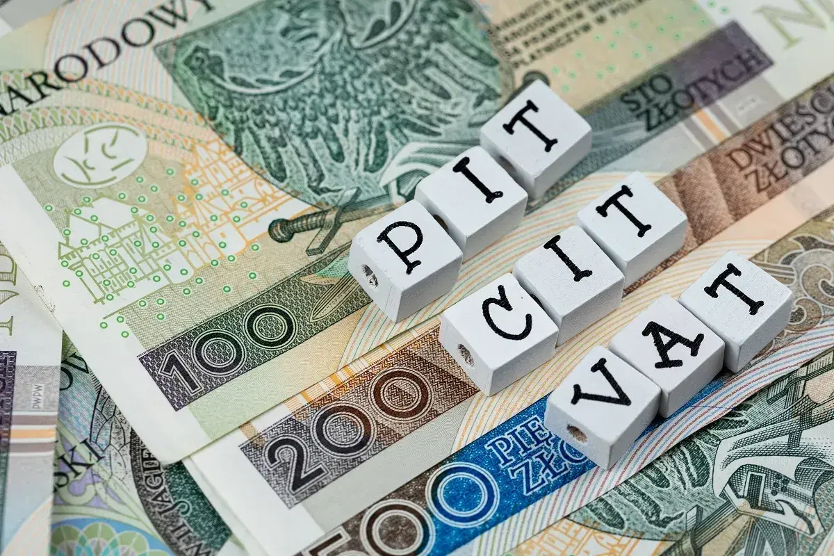 Polskie banknoty z napisami PIT i VAT. Ulga na złe długi może pomóc w rozliczeniu podatków.