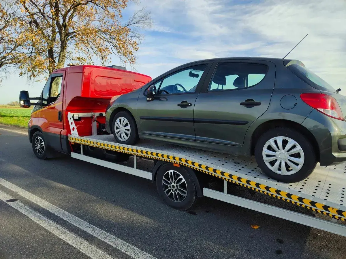 Holowanie pojazdu. Na lawecie stoi ciemnoszary samochód. To może być związane z art. 178a kk.