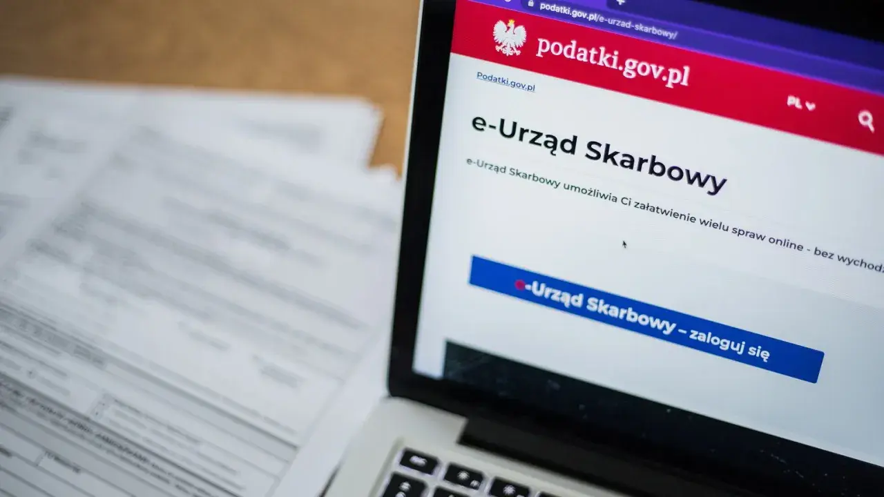Laptop z otwartą stroną e-Urzędu Skarbowego. Obok leżą dokumenty, co sugeruje identyfikację zobowiązania podatkowego.