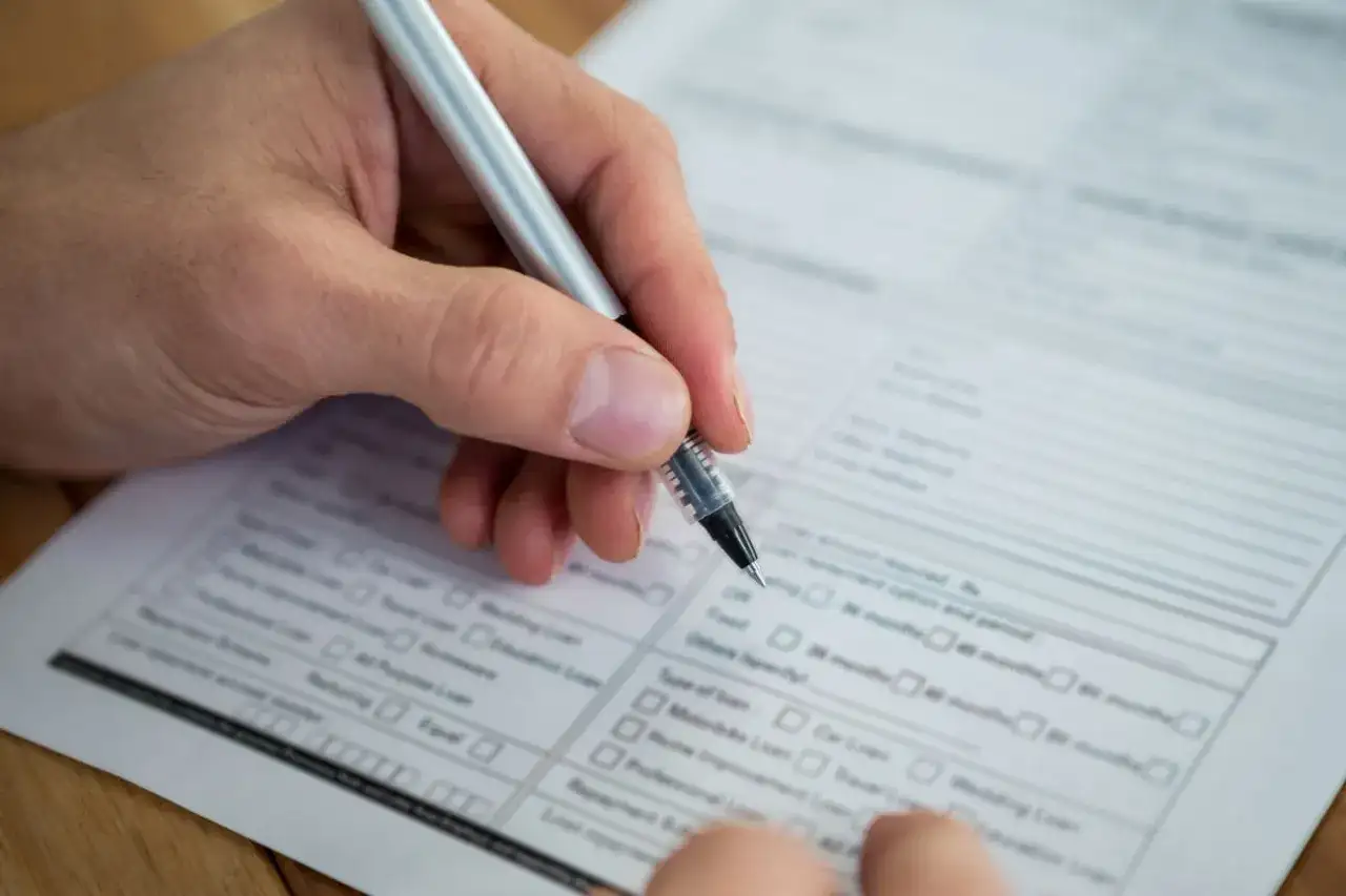 Dłoń z długopisem wypełnia formularz. Warto wiedzieć, jak sprawdzić swój NIP, by poprawnie wypełnić dokumenty.