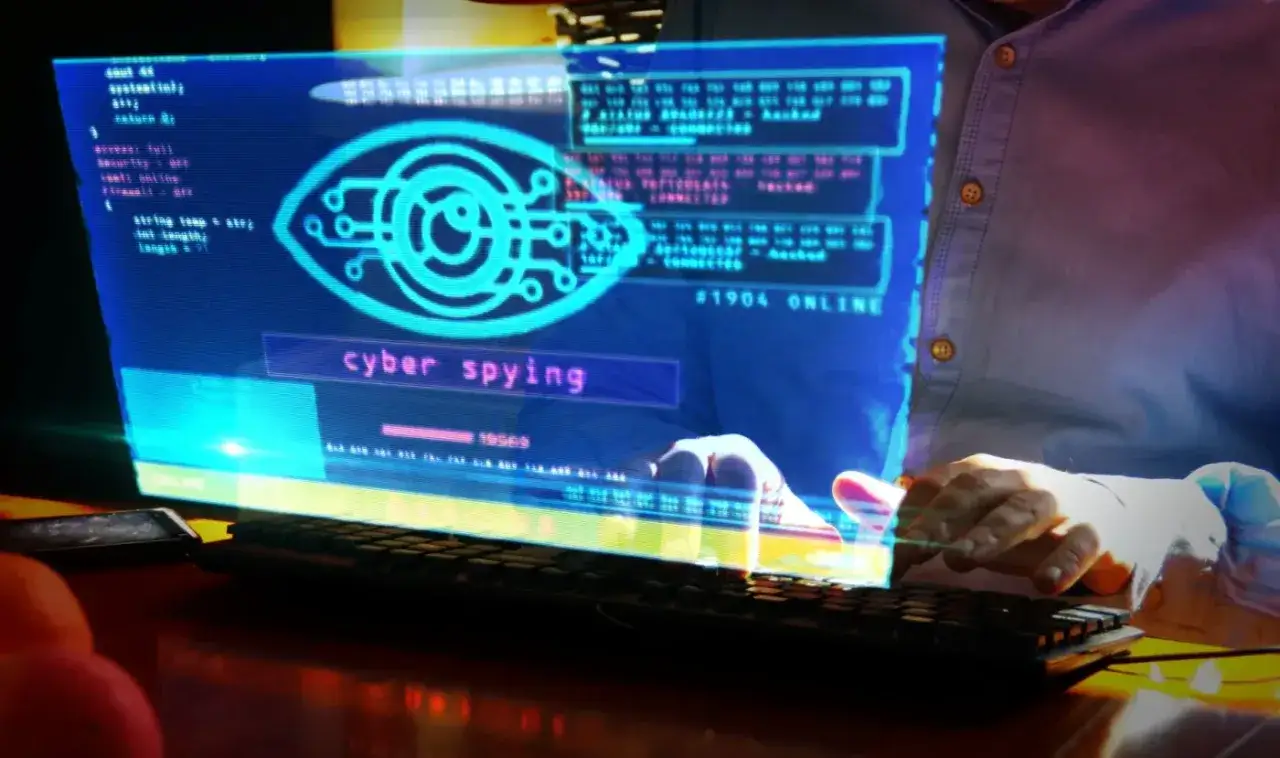 Cyber spying, co to? Holograficzny ekran z okiem symbolizującym inwigilację i kodem. Dłonie użytkownika nad klawiaturą.