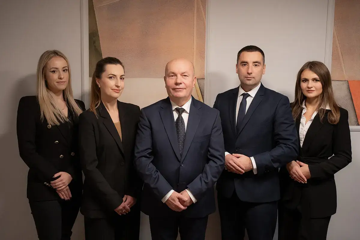 Pięć osób w garniturach stoi w rzędzie.