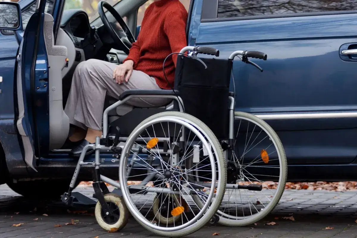 Osoba w wózku inwalidzkim wsiada do samochodu. To ułatwienie w podróży, dzięki któremu ulga rehabilitacyjna na samochód jest dostępna dla każdego.