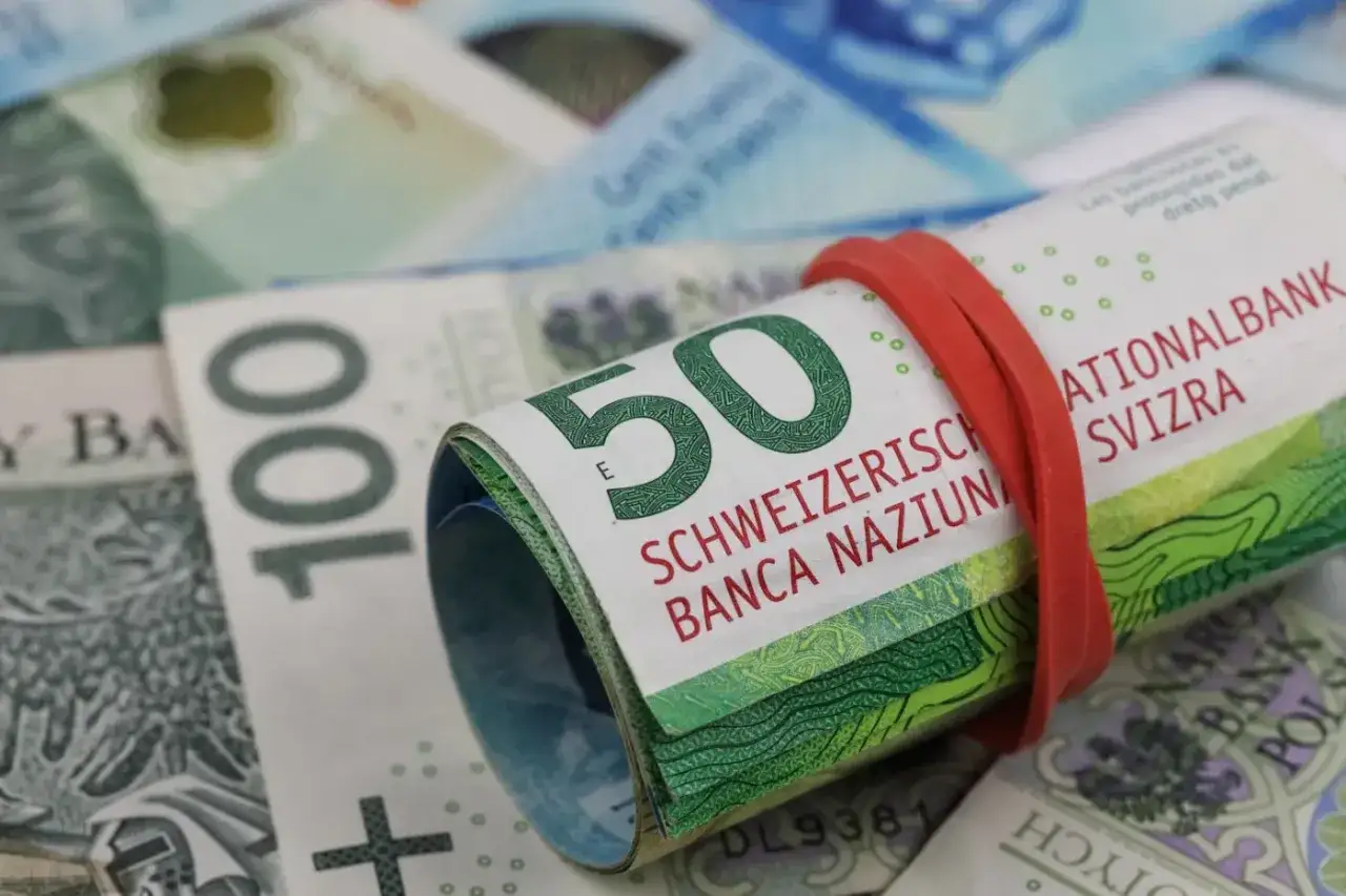 Zwijane banknoty 50 i 100 franków szwajcarskich, otoczone gumką. Symbolizują pieniądze i potencjalne przedawnienie długu.