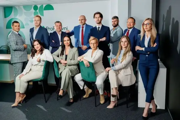 Zespół prawników w garniturach, pozujący do zdjęcia w nowoczesnym biurze.
