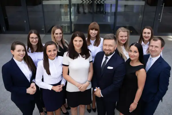 Grupa prawników w garniturach i strojach biznesowych przed budynkiem.