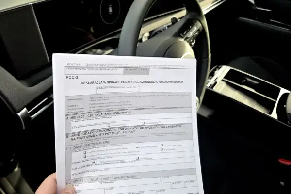 Formularz PCC-3, deklaracja podatku od czynności cywilnoprawnych, leży na kierownicy samochodu.
